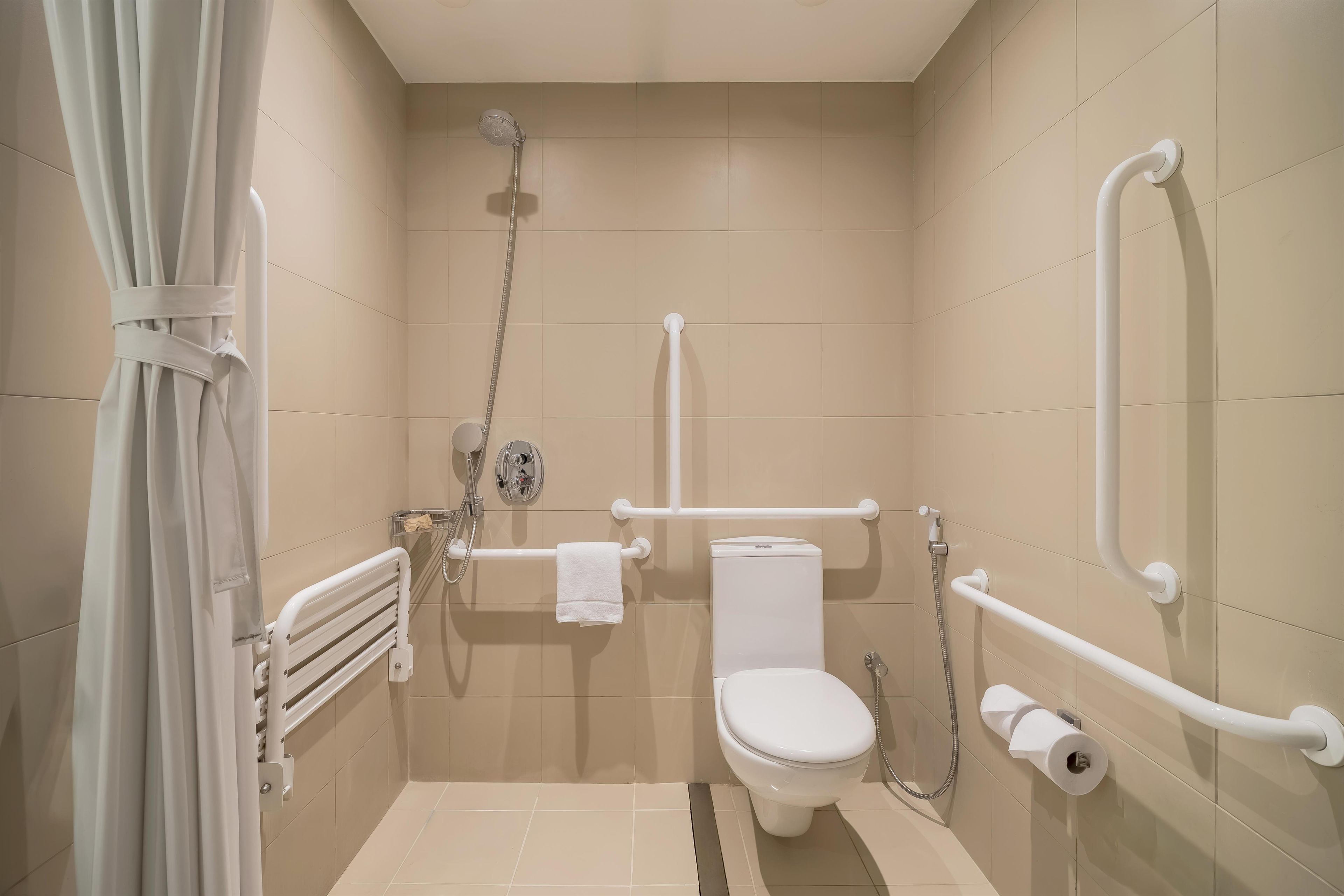 A bathroom with a toilet, shower, and grab bars.