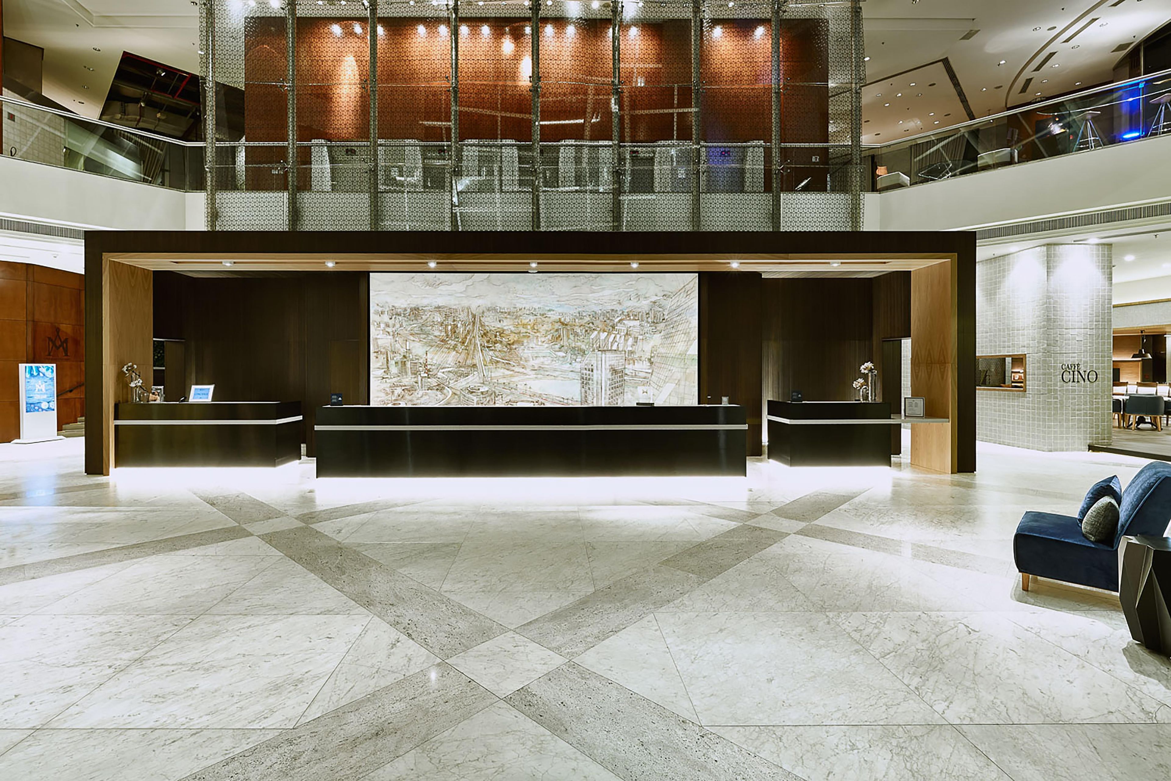 A spacious lobby with a reception desk, a large abstract mural, and a seating area with a sofa.