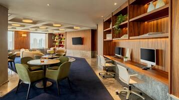 A modern hotel lobby with a seating area, a reception desk, and a large window offering a city view.