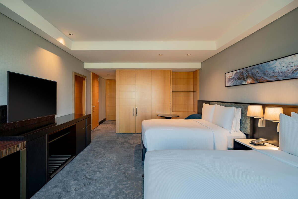 Una habitación de hotel con una cama grande, televisión, escritorio y armario.