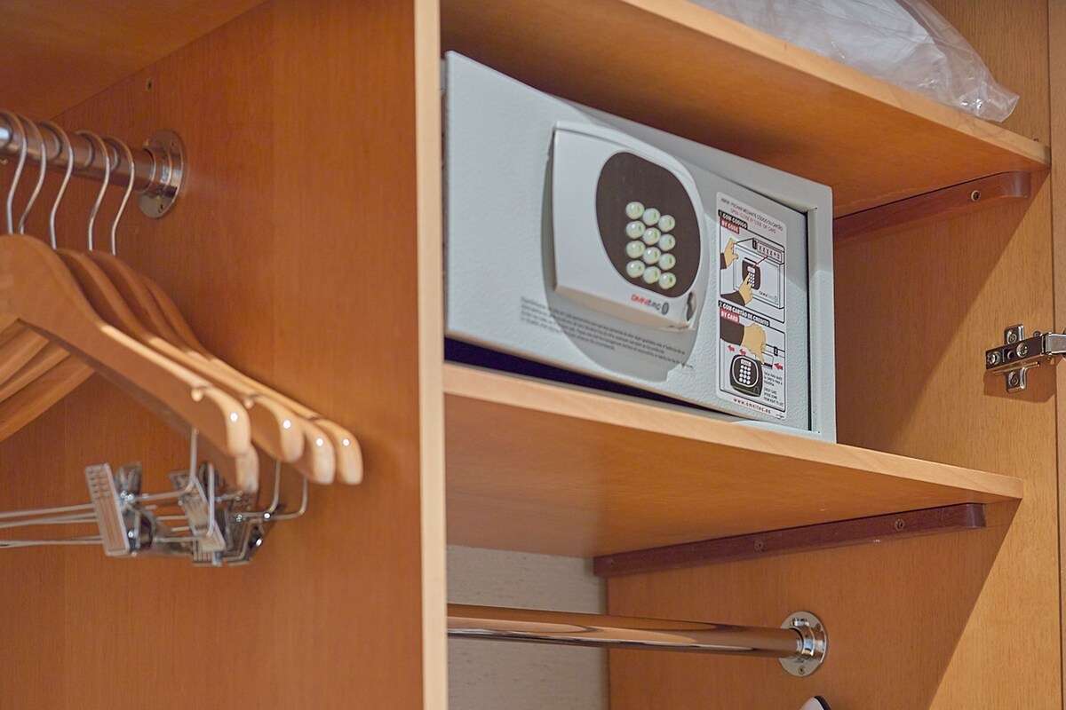 Een compacte badkamer met een douche, toilet en een klein kastje met een haardroger.