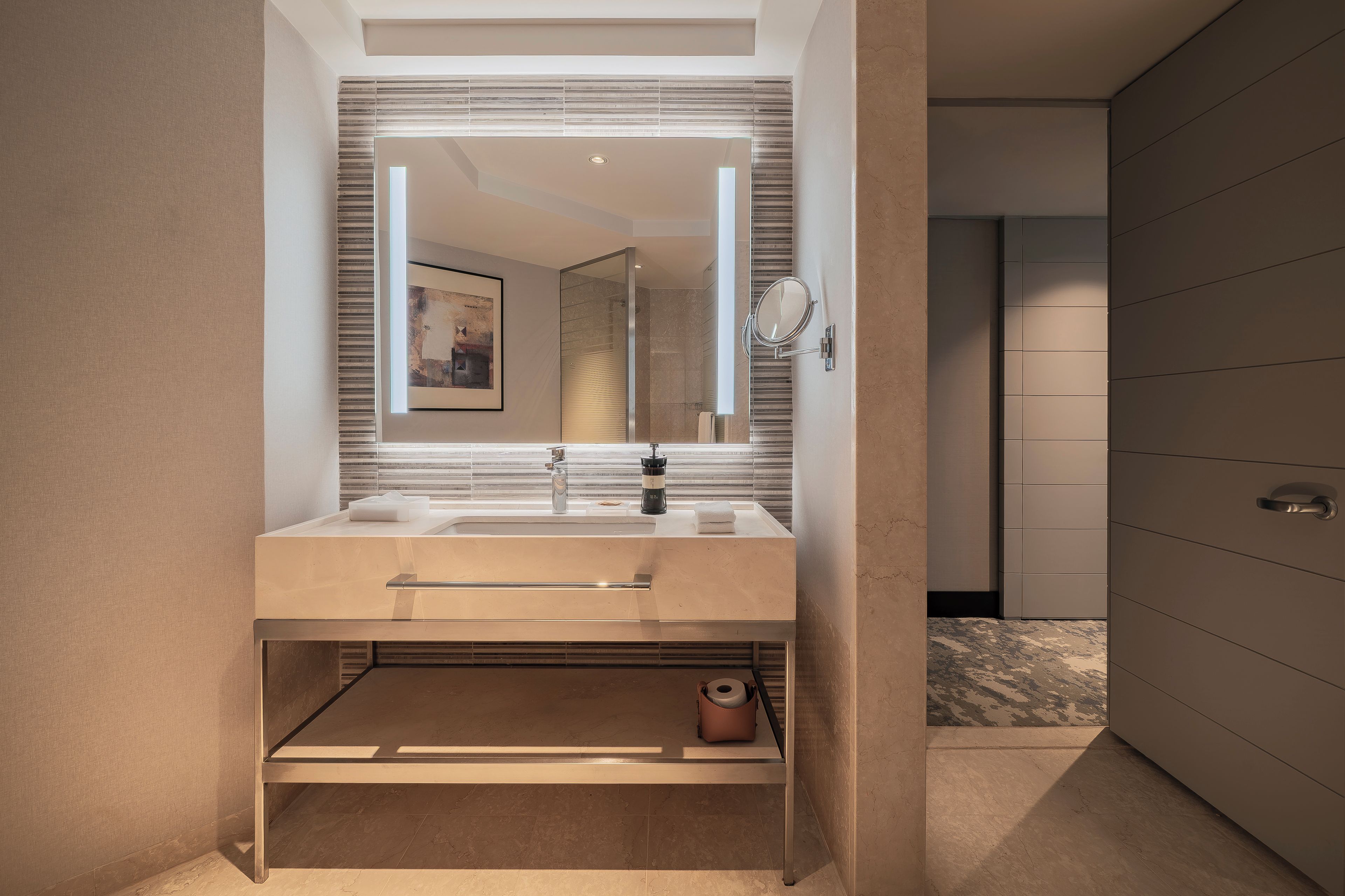 Une salle de bain moderne avec un grand miroir, deux vasques et un porte-serviettes.