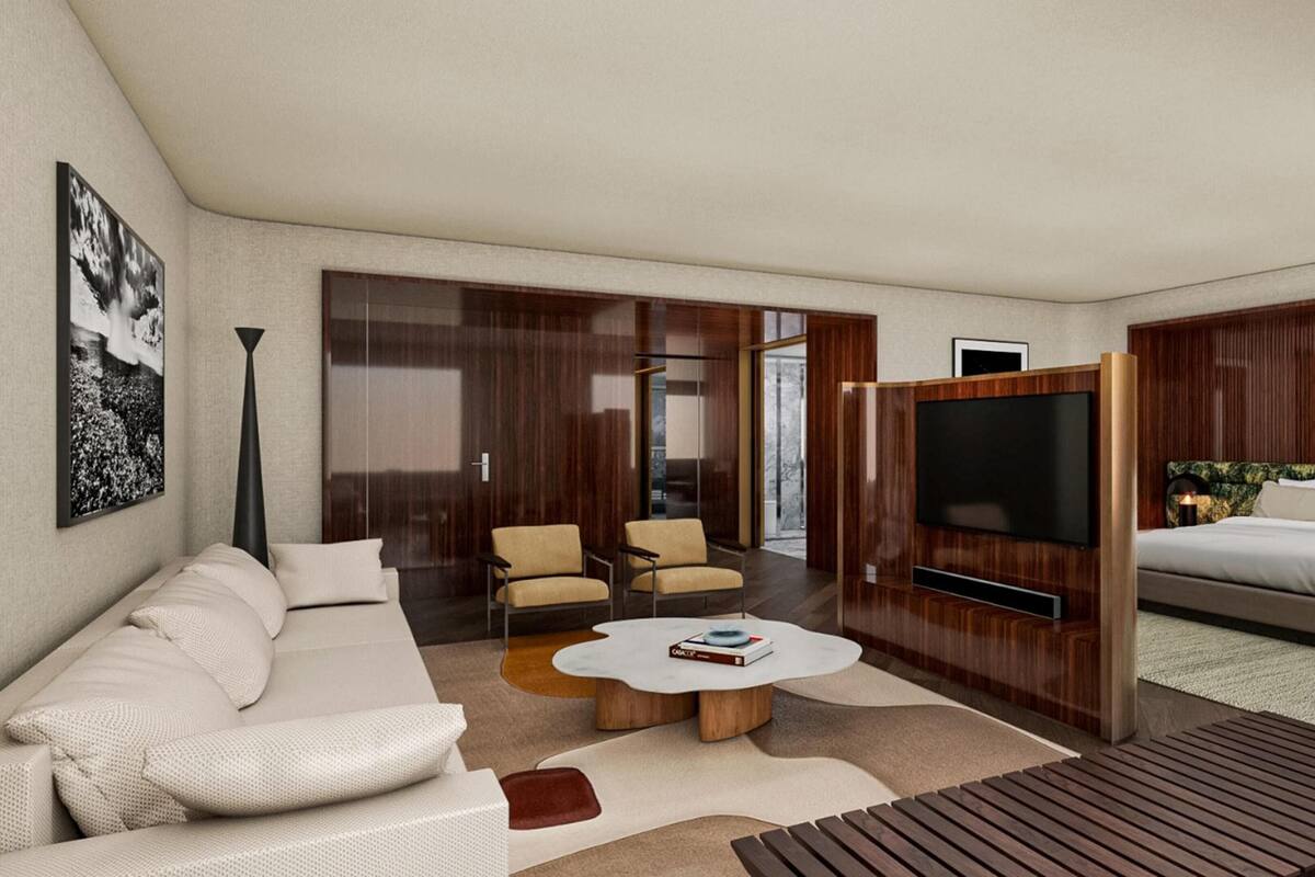 Una habitación de hotel moderna con sofá, sillones, una mesa de centro, televisor y cama.