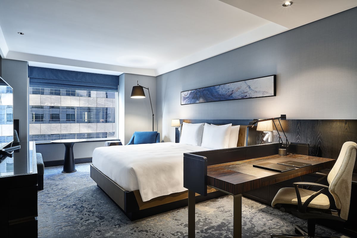 Una habitación de hotel moderna con una cama grande, un escritorio y vistas a la ciudad.