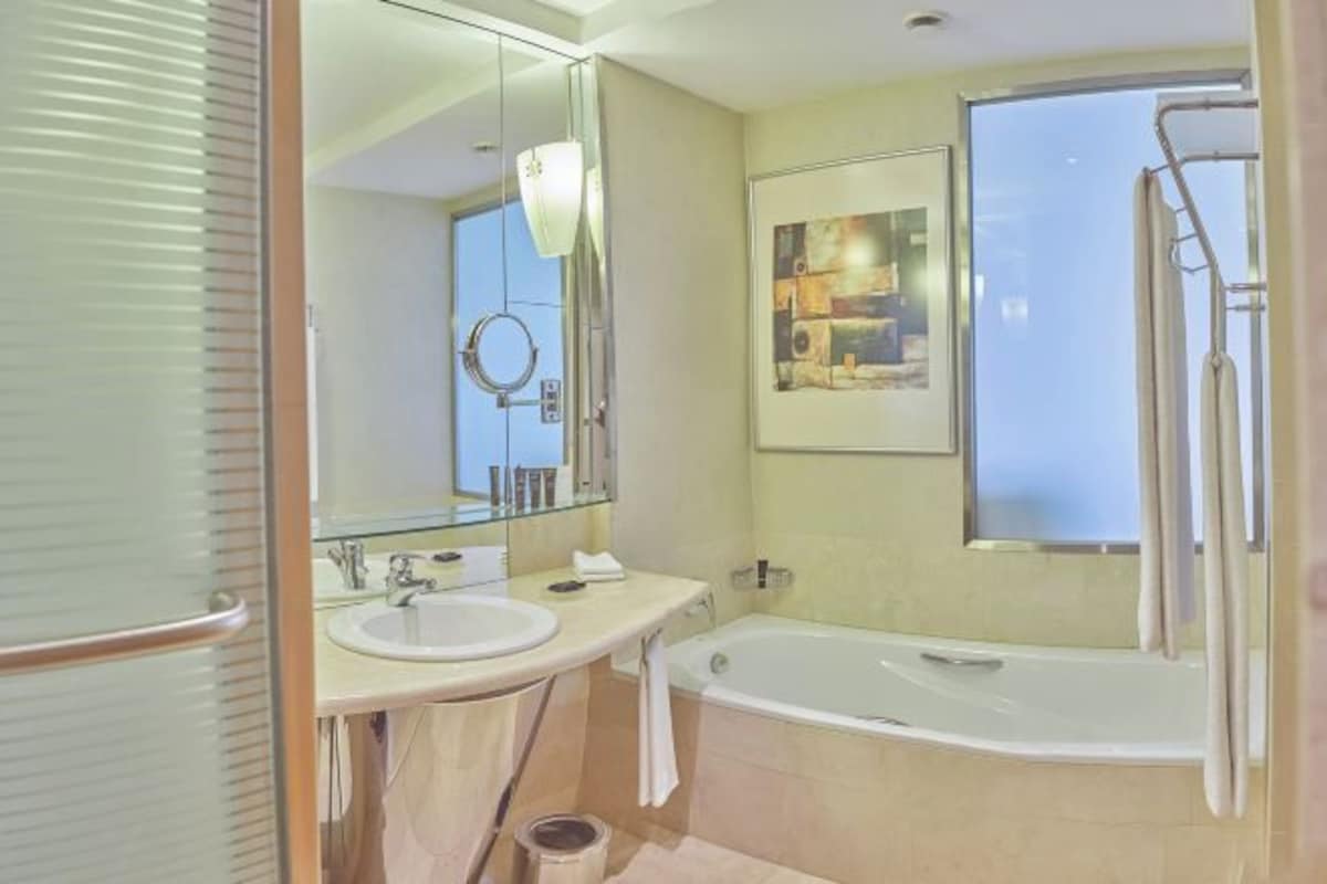 A modern bathroom with a bathtub, two sinks, a large mirror, and a shower.