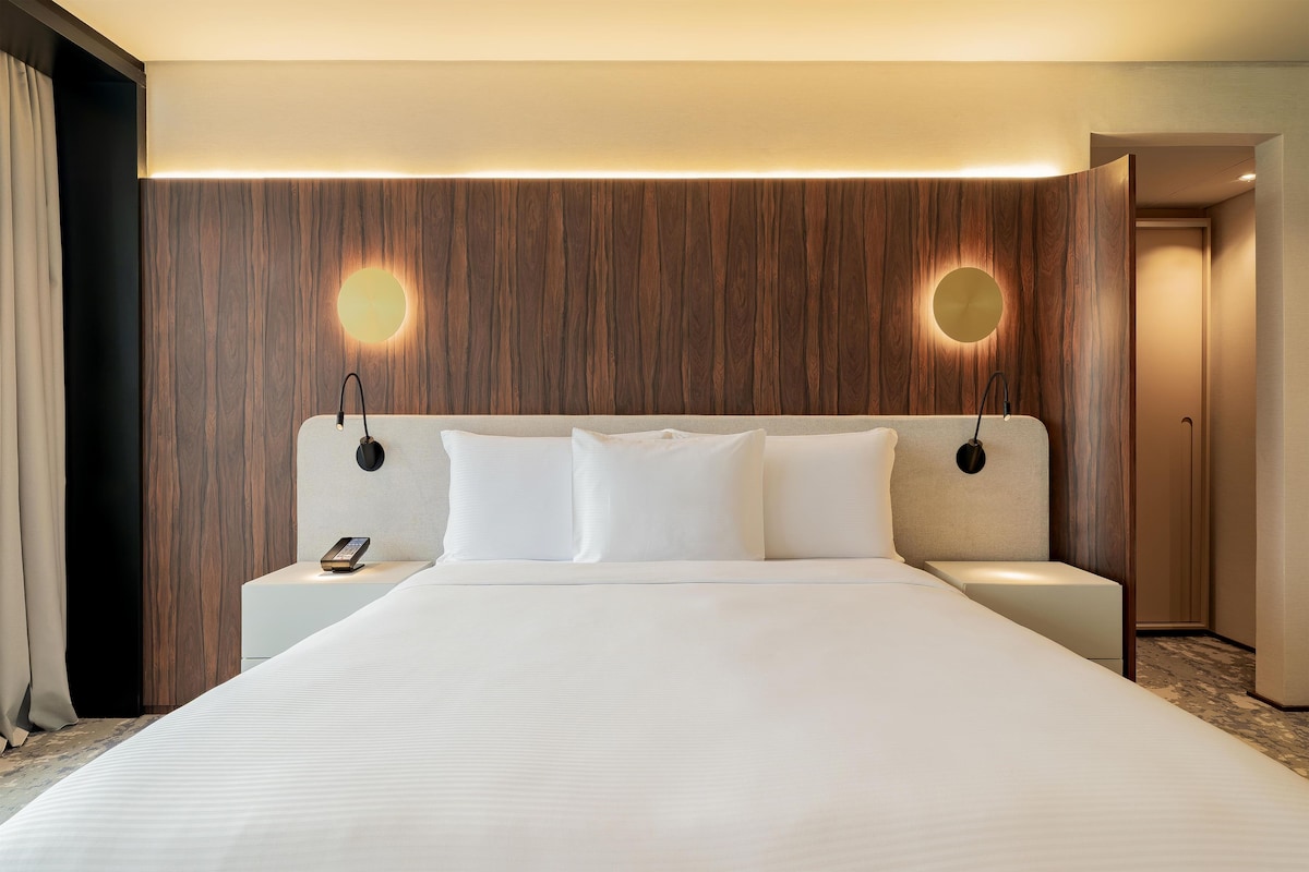 Een hotelkamer met een groot bed, twee nachtkastjes en een houten accentmuur.