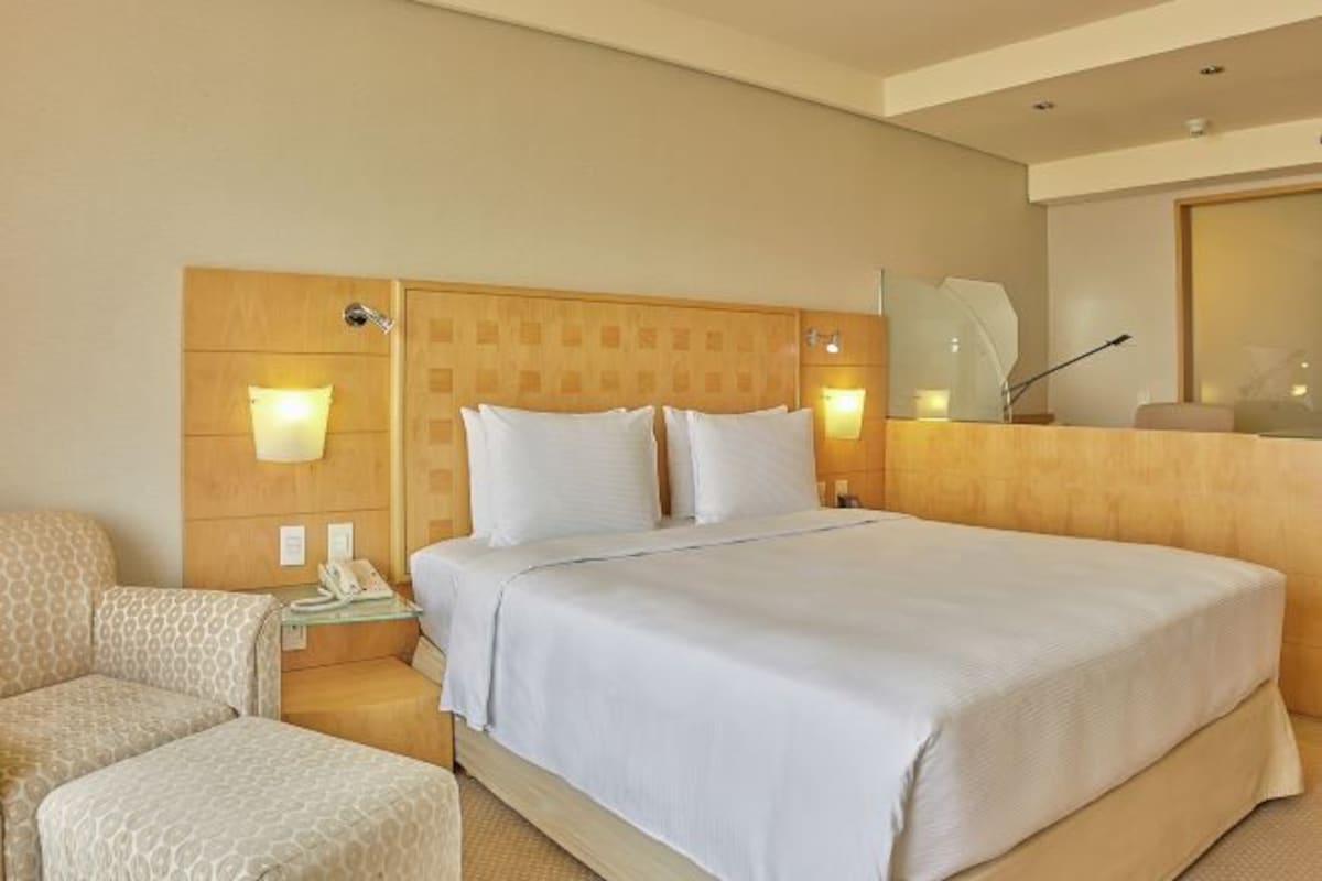 A hotel room with a large bed, two bedside tables, a chair, and a mirror.