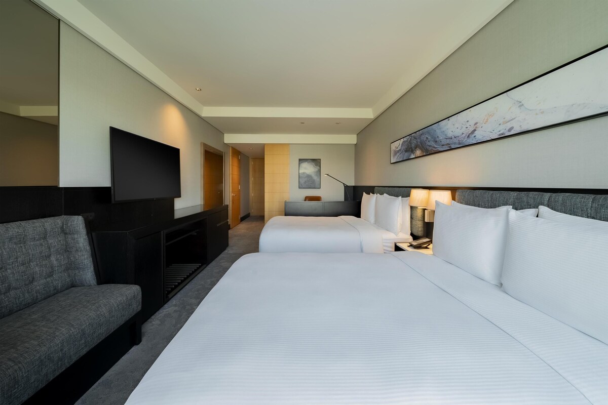 Ett hotellrum med en stor säng, en soffa, en platt-TV och en tavla på väggen.