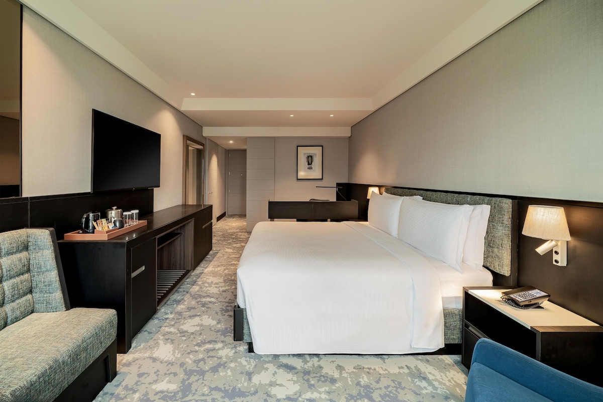 Een hotelkamer met een bed, een bureau, een stoel, een televisie en een badkamer.