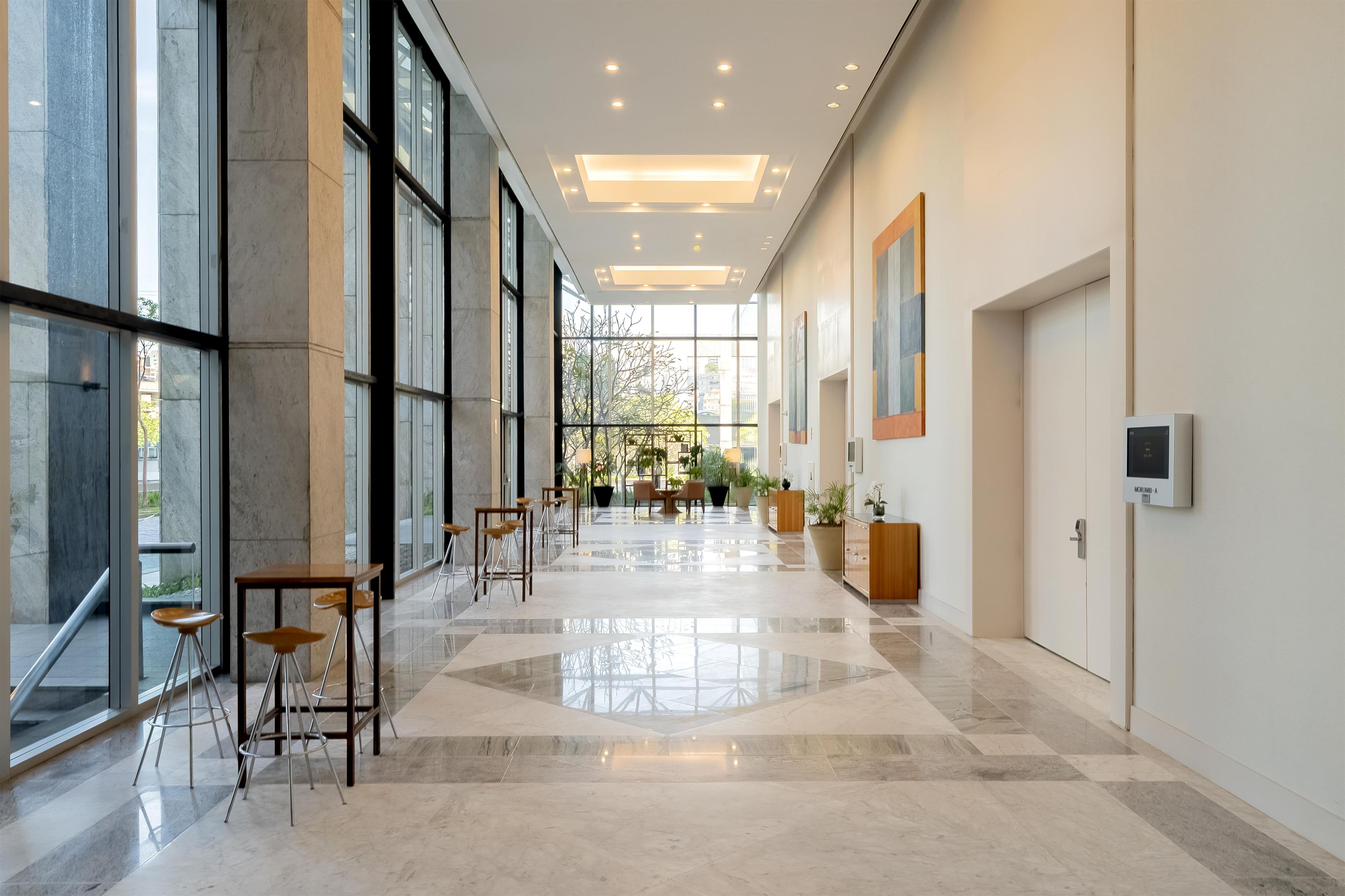 Um amplo hall de hotel com janelas grandes, uma área de estar central e um design moderno.