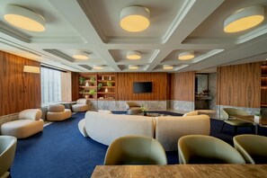 Een moderne zithoek met meubels, een flatscreen televisie en houten lambrisering.