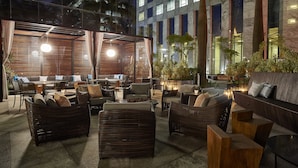 An outdoor seating area with wicker furniture, a stone wall, and a view of a modern building.