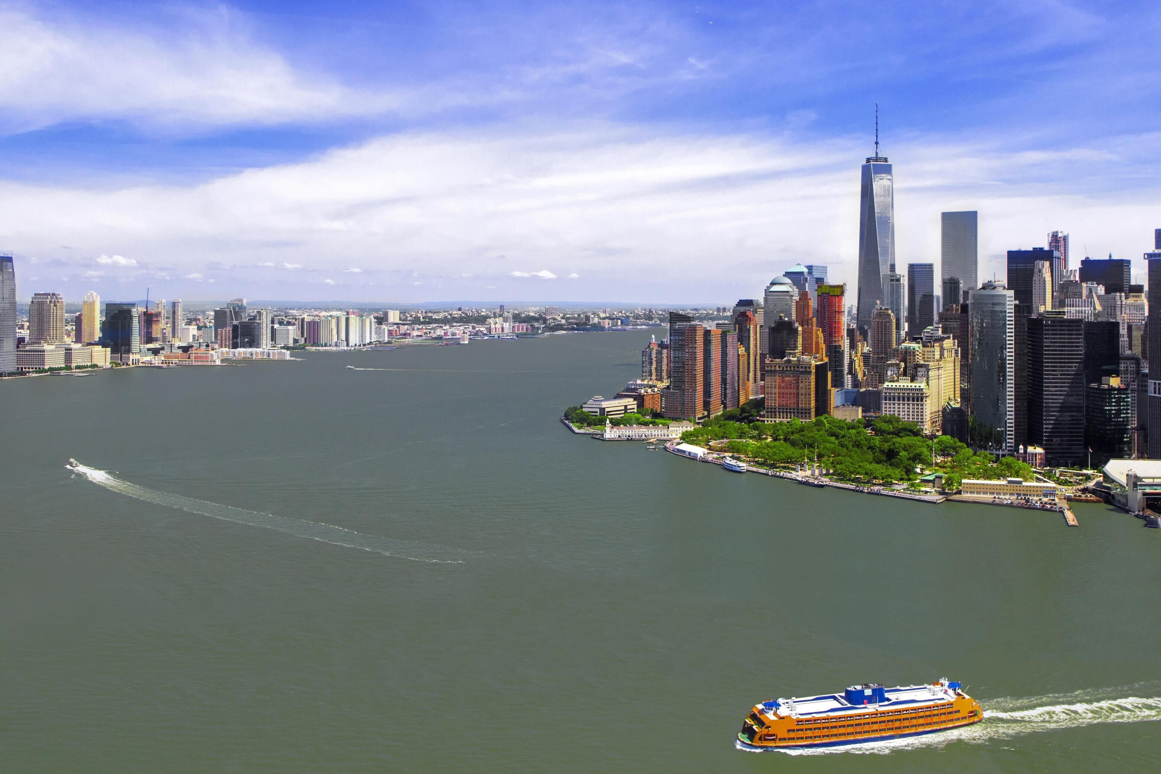A river with a cruise ship in the foreground and a city skyline in the background.