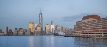 A waterfront hotel with a view of a city skyline, including a prominent skyscraper.