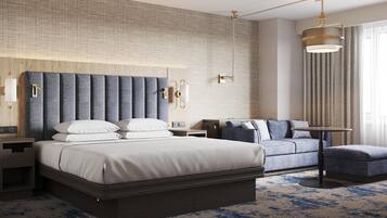 A hotel room with a large bed, a sofa, a small table, and a wall-mounted light fixture.