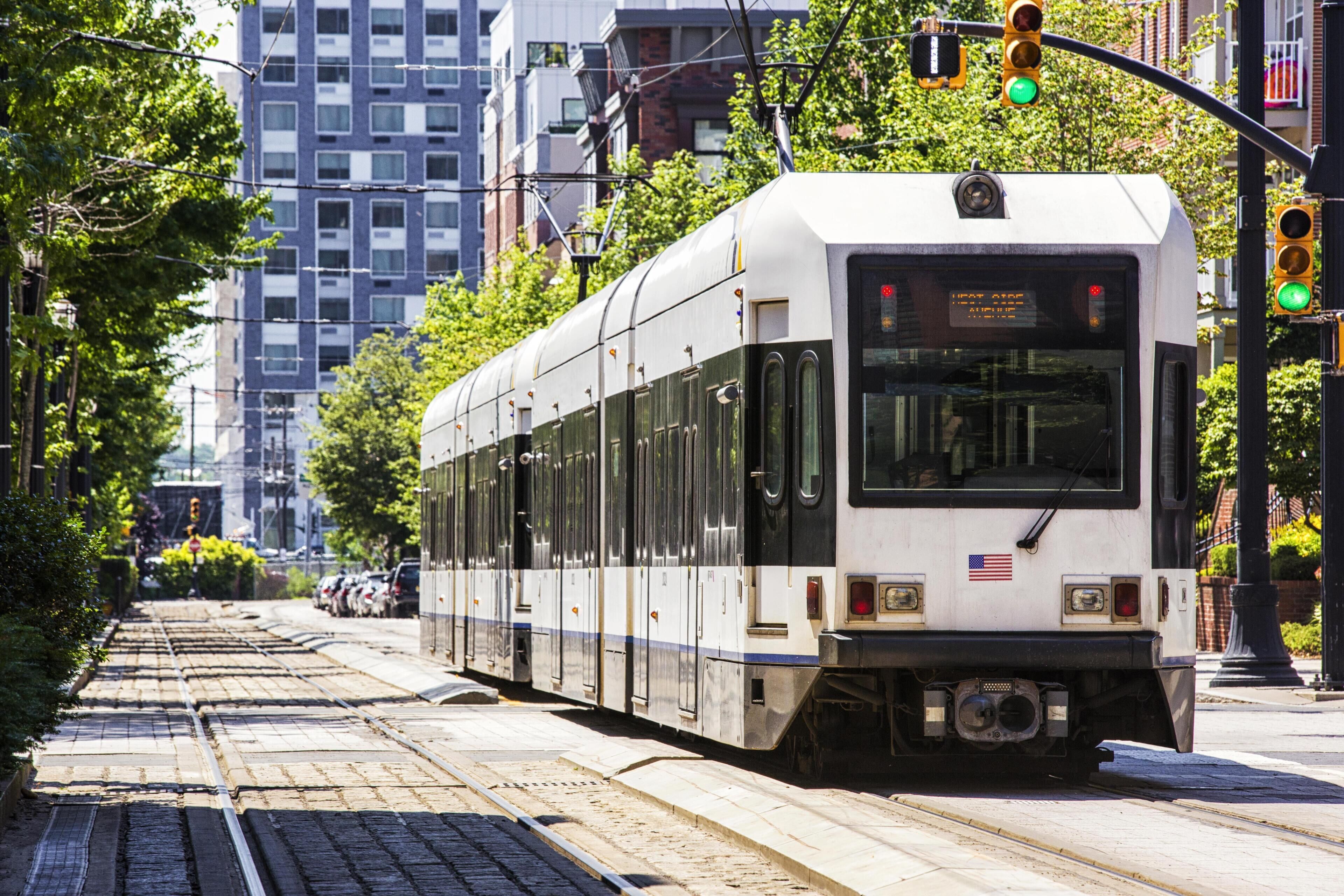 A tram on tracks with buildings and trees in the background.