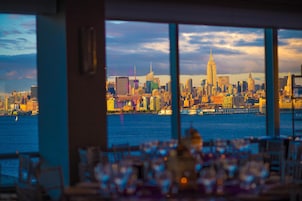 Vista del horizonte urbano desde una ventana con vistas a un cuerpo de agua, y un área de comedor al frente.