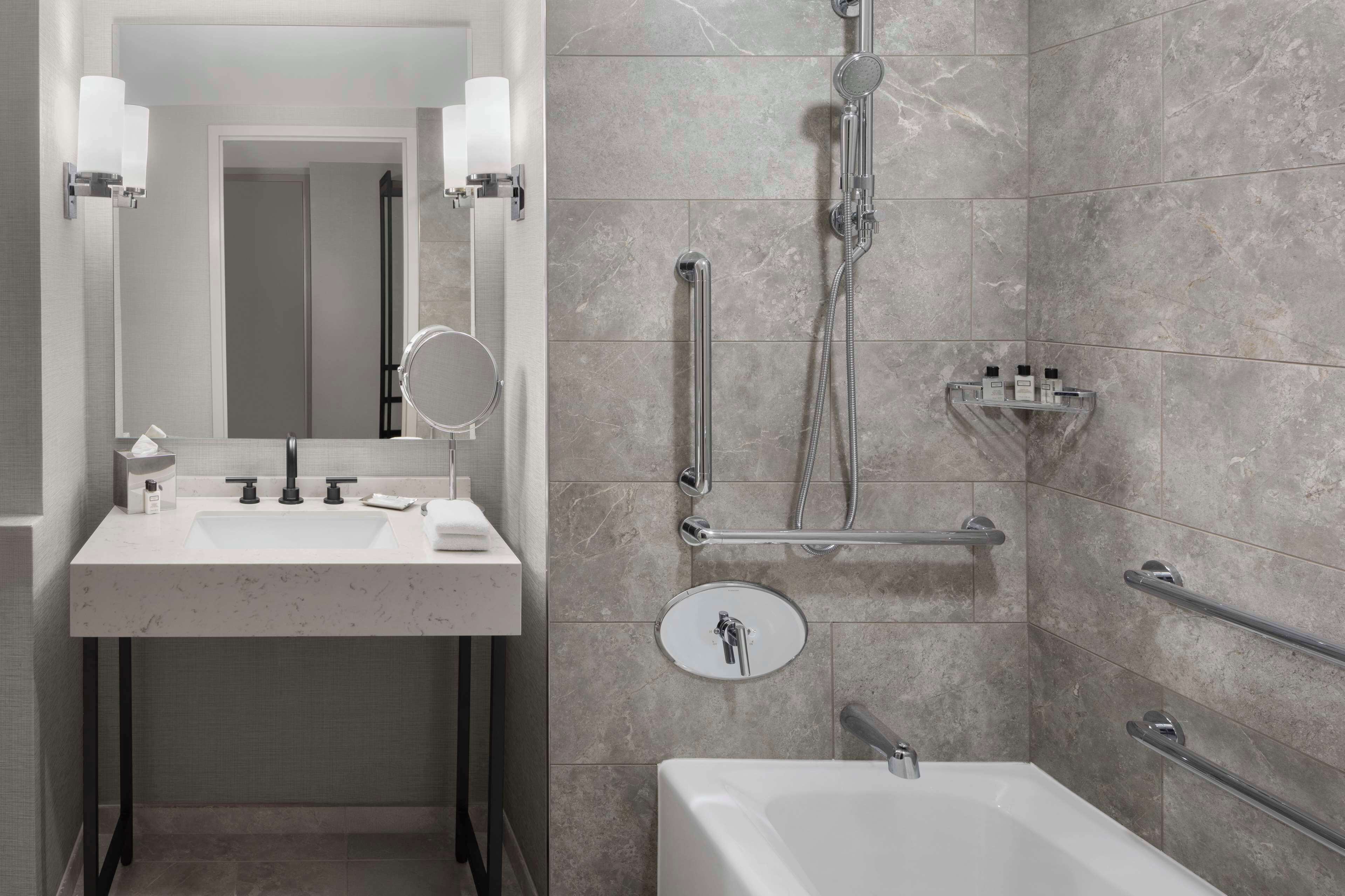 Un baño moderno con lavamanos, espejo y ducha.