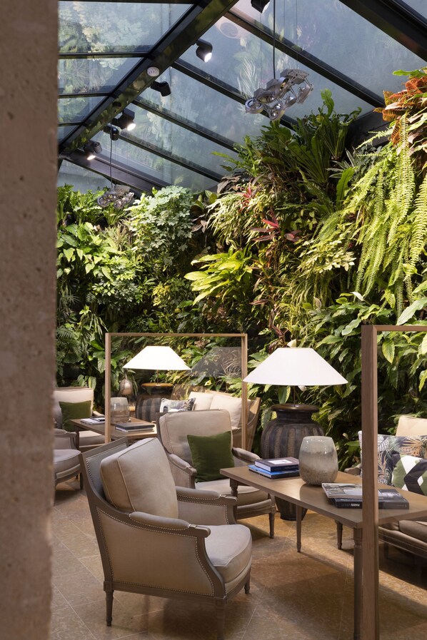 A conservatory with seating, plants, and hanging lights. - Hotel Pas De Calais (Paris)
