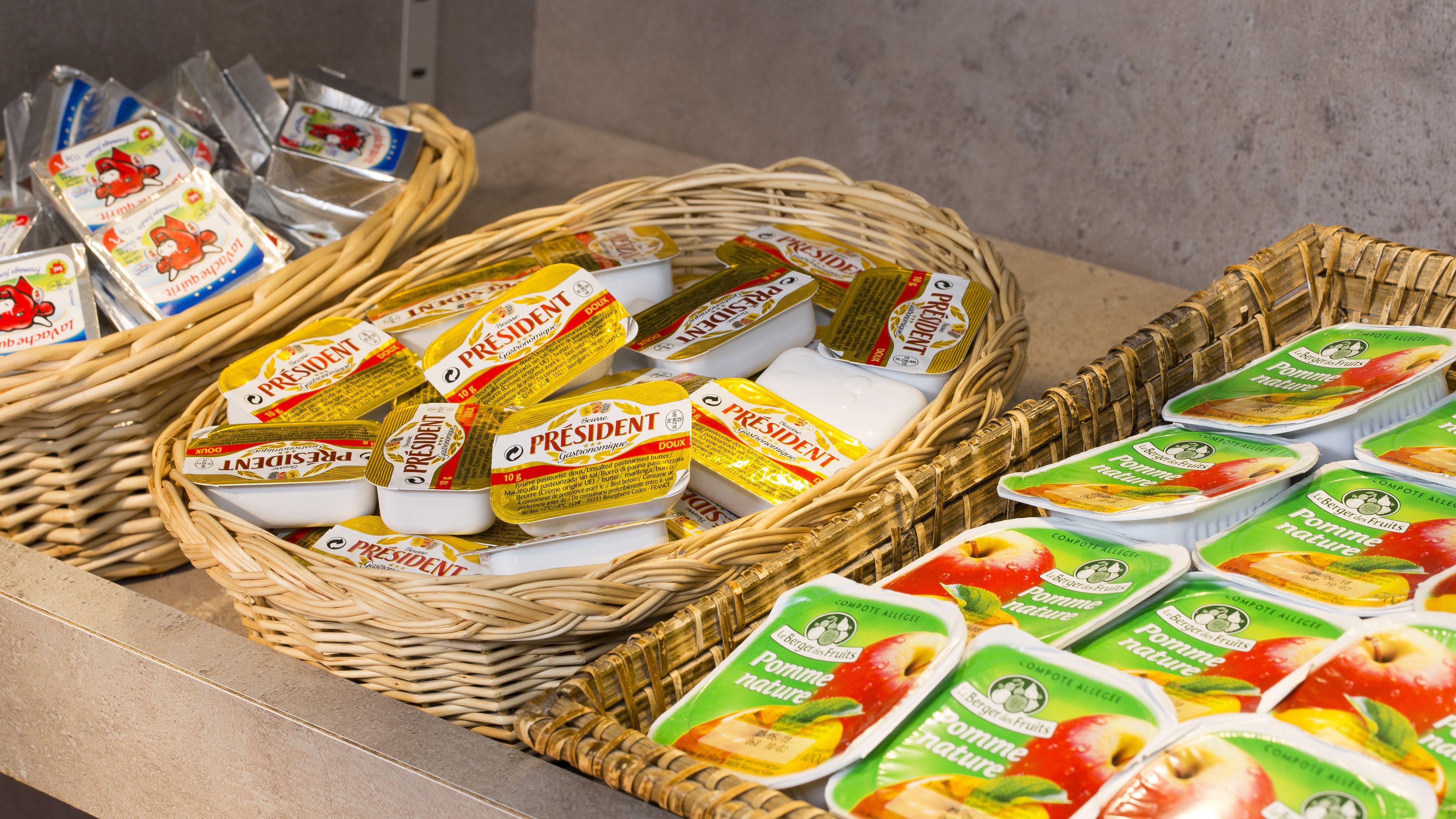 Körbe gefüllt mit verpackten Lebensmitteln, darunter Käse und Fruchtnussjoghurt.