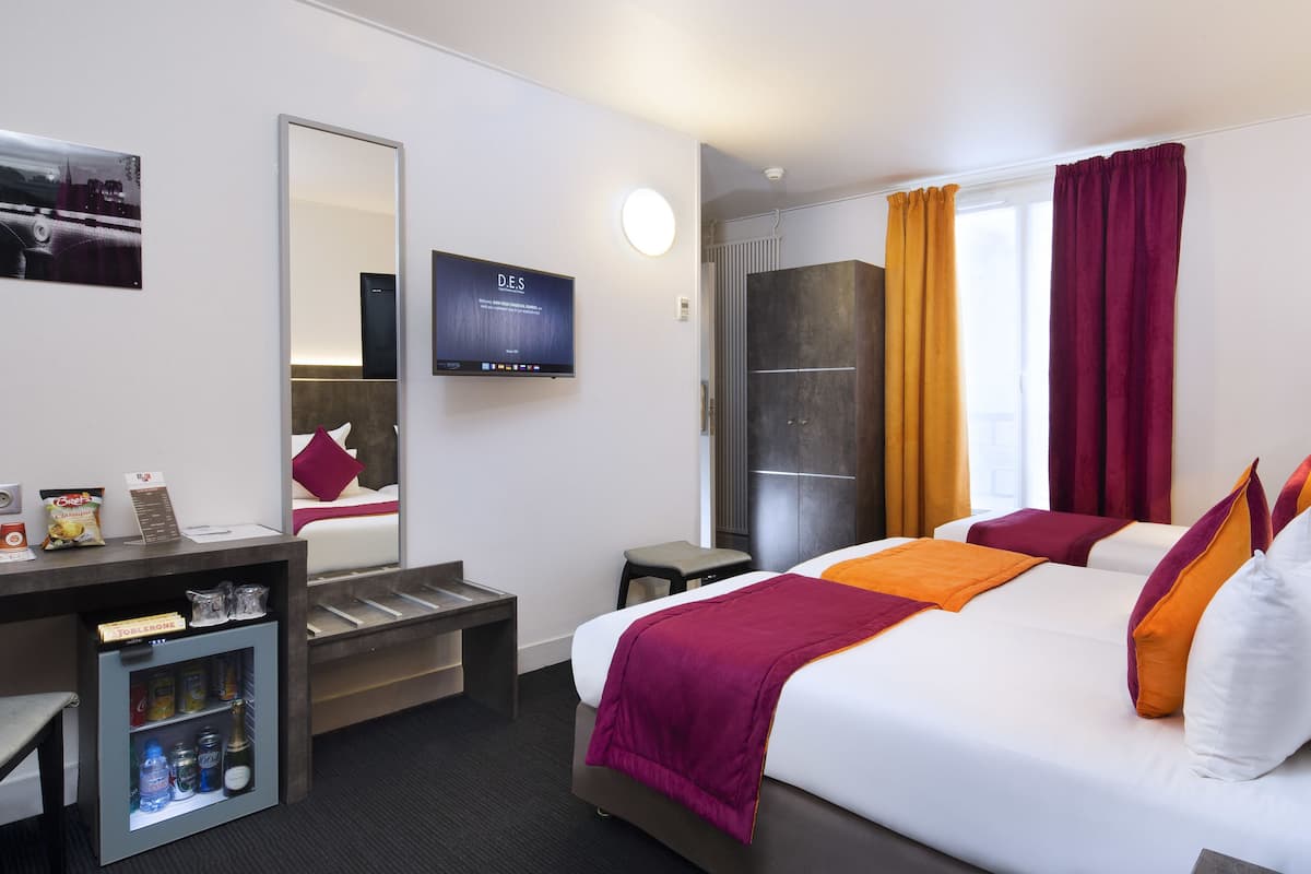 Una habitación de hotel con una cama, un escritorio con computadora, televisor y un minibar.