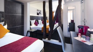 Una habitación de hotel moderna con una cama grande, un escritorio con cafetera y vista al pasillo.