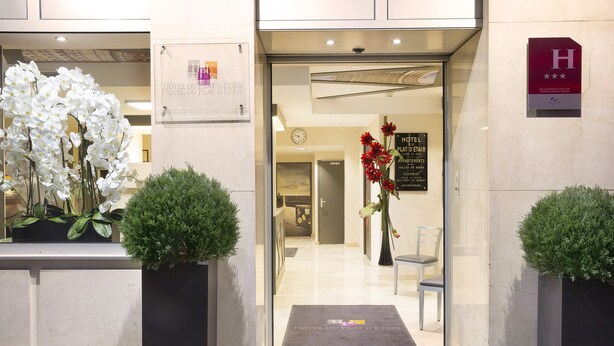 Entrada de un hotel con mostrador de recepción, un reloj y un cartel con el nombre del hotel.
