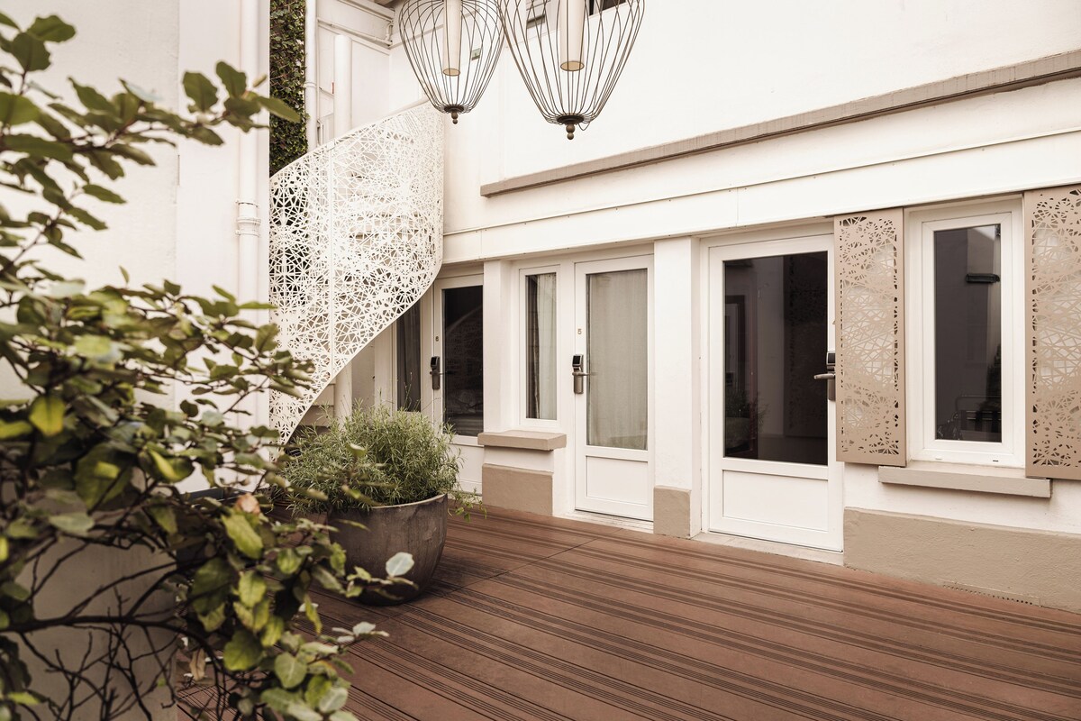 Un bâtiment moderne doté d’une terrasse en bois, de murs blancs et de panneaux décoratifs.