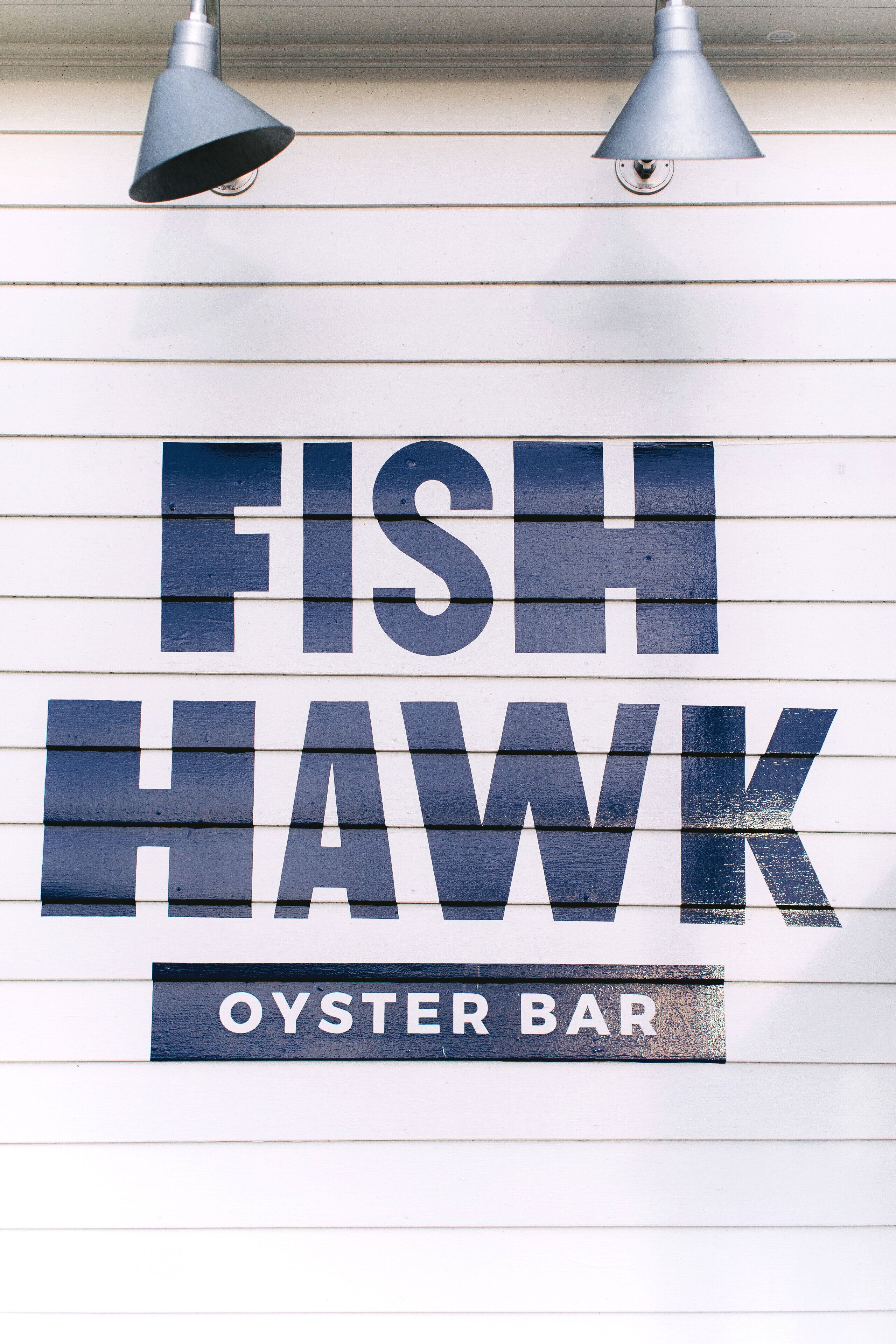 A sign for a fish and hawk oyster bar.