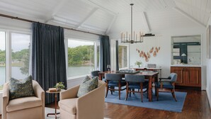 A spacious living room with a view of a lake, a dining area with a chess table, and a kitchen with a large mirror. - The Tides Inn (Irvington)