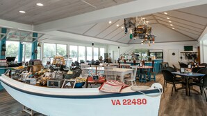 A restaurant with a boat-shaped counter, wooden ceiling, and large windows. - The Tides Inn (Irvington)