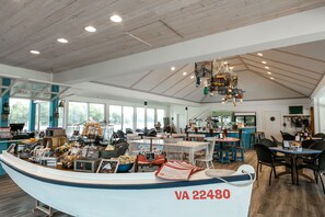A restaurant with a boat-shaped counter, wooden ceiling, and large windows. - The Tides Inn (Irvington)