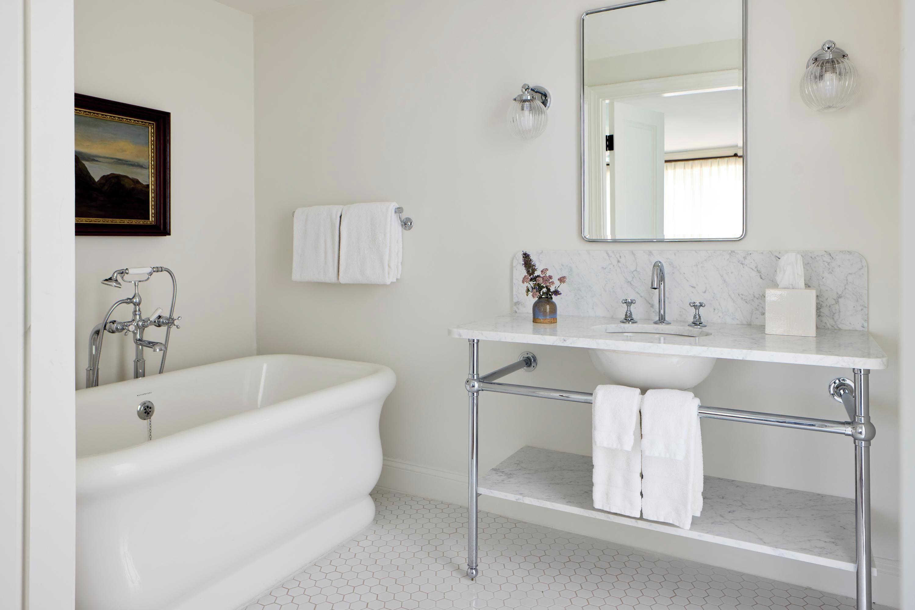 A bathroom with a freestanding bathtub, a vanity with a mirror, and a toilet.