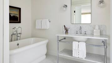 A bathroom with a freestanding bathtub, a vanity with a mirror, and a toilet.