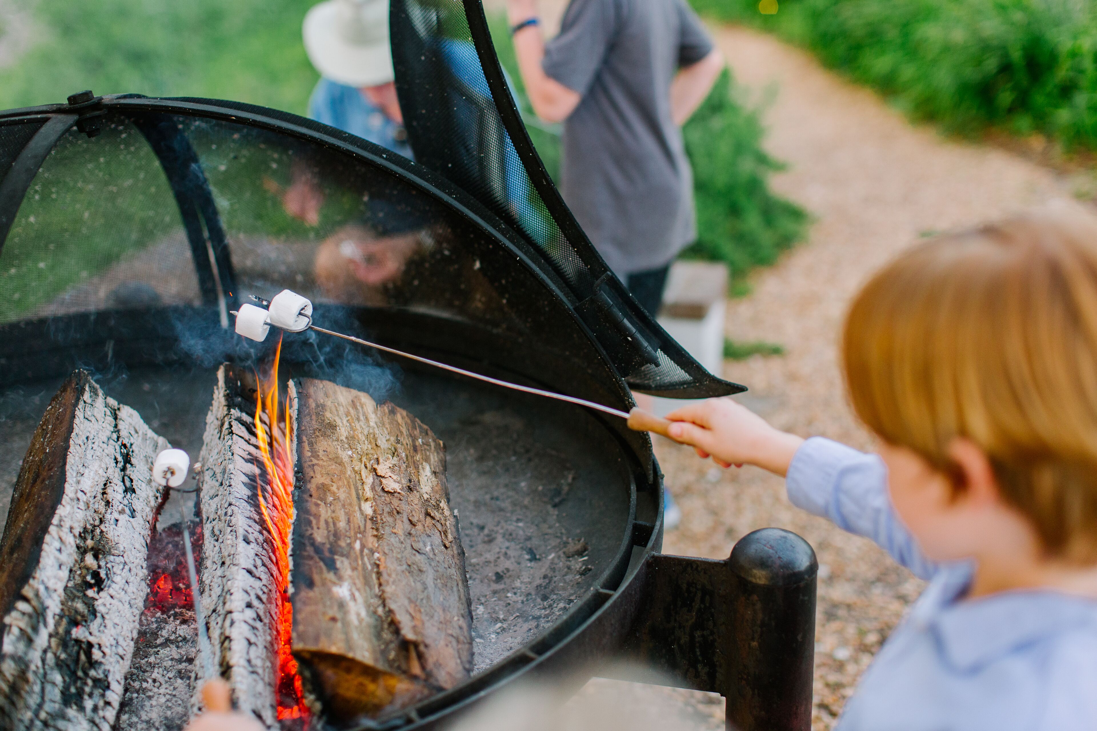 A person roasting marshmallows over an open fire in a grill.
