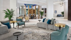 A spacious lobby with a modern design, featuring sofas, armchairs, and a coffee table.