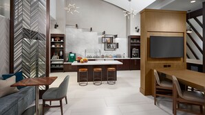 A modern kitchen with a central island, bar stools, and a dining table.