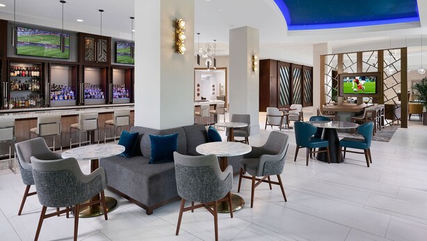 A modern bar area with seating, a sports screen, and a ceiling with a starry design.