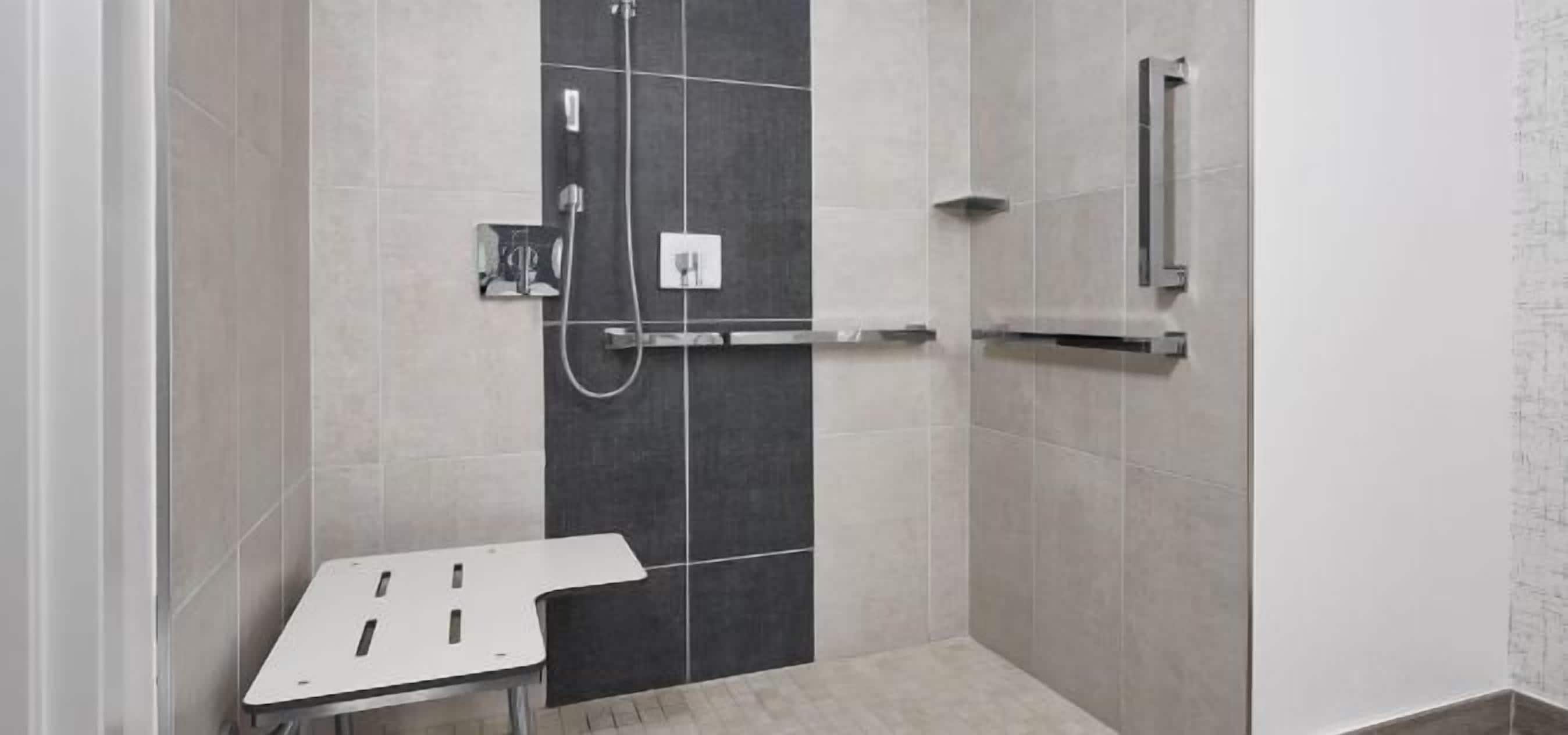 A shower area with a control panel, a towel rack, and a small table.