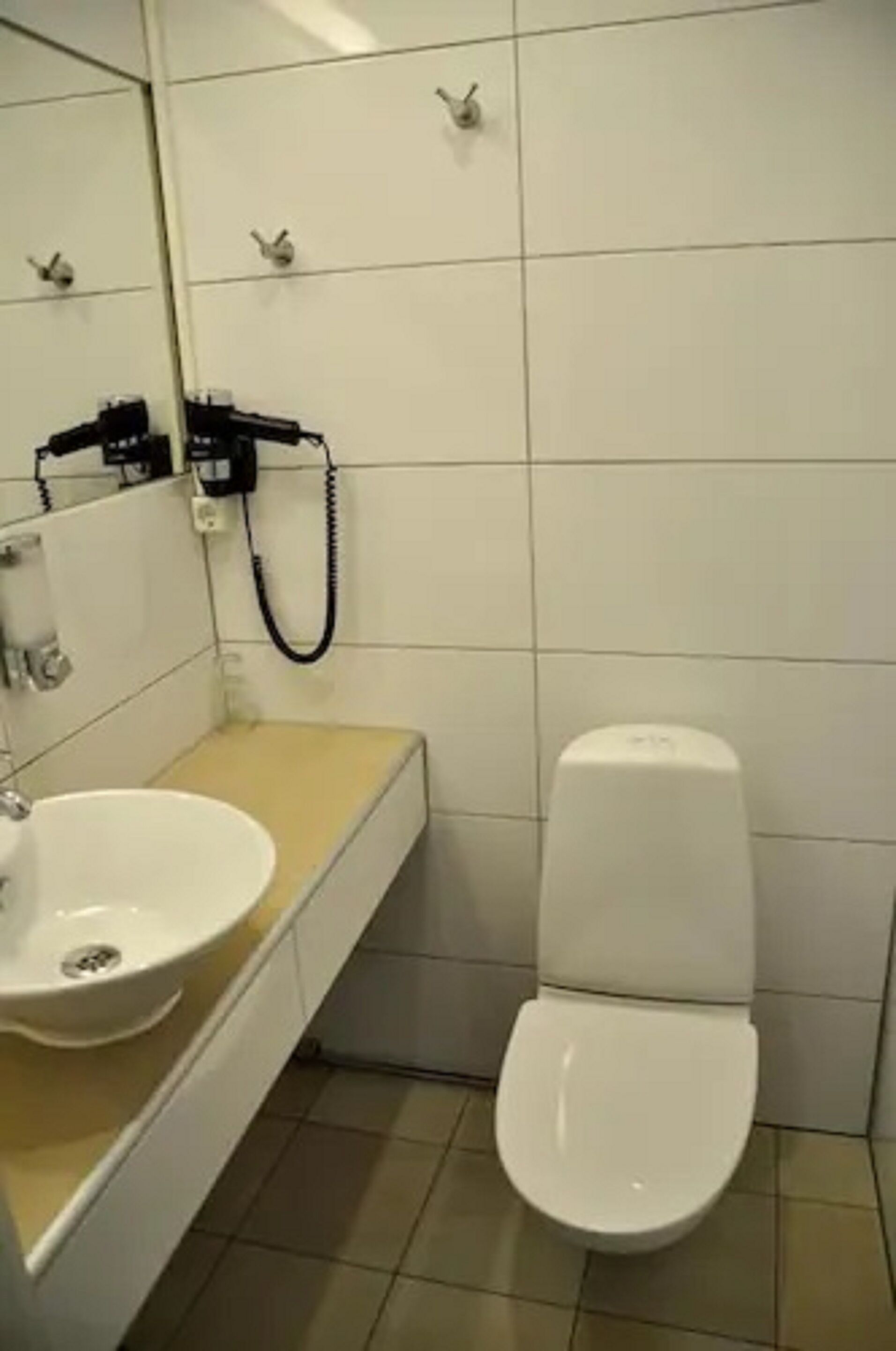 A bathroom with a white sink, mirror, and toilet.