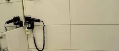 Un baño con lavamanos, espejo y retrete blanco.
