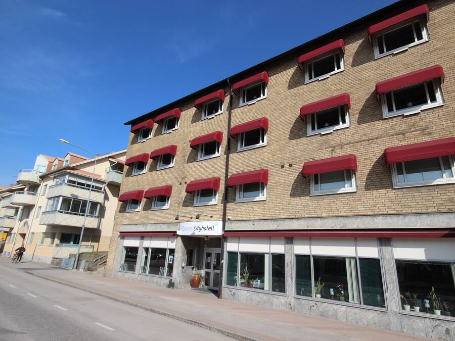 A multi-story hotel with red awnings and a sign reading "Cityhotel".