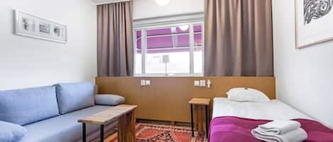 Una camera d'albergo con un divano, un letto, un tavolino e una finestra con tende.