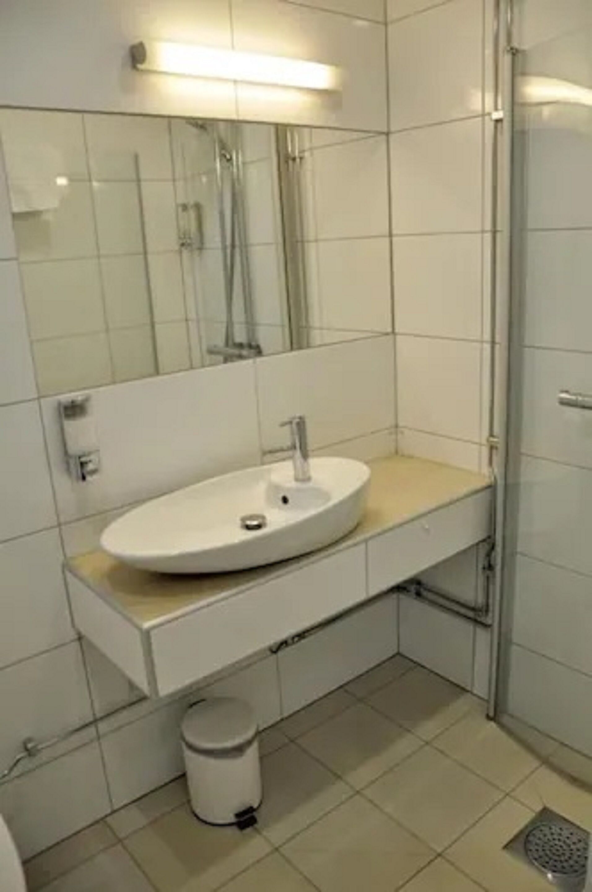 Et moderne badeværelse med hvid vask, spejl og brusebad.