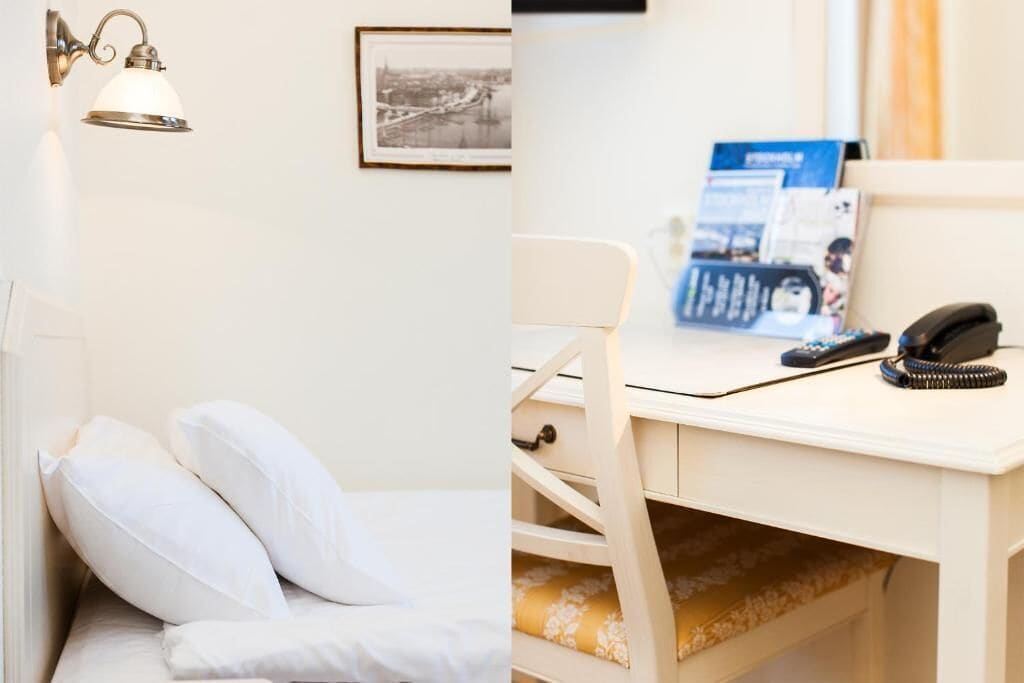 Een hotelkamer met een bed, een bureau met telefoon en een lijst als decoratie aan de muur.