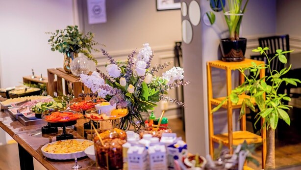 Une table de buffet garnie de divers plats et agrémentée d’un arrangement floral.