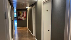 Un couloir doté d’un plancher en bois, de portes blanches et d’un plafond pourvu d’un éclairage encastré.