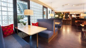 A modern restaurant with wooden flooring, blue seating, and pendant lighting. - Break Sokos Hotel Eden (Oulu)