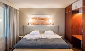 A modern hotel room with a large bed, two bedside tables, a nightstand, a wall-mounted lamp, and a large artwork above the bed. - Break Sokos Hotel Eden (Oulu)