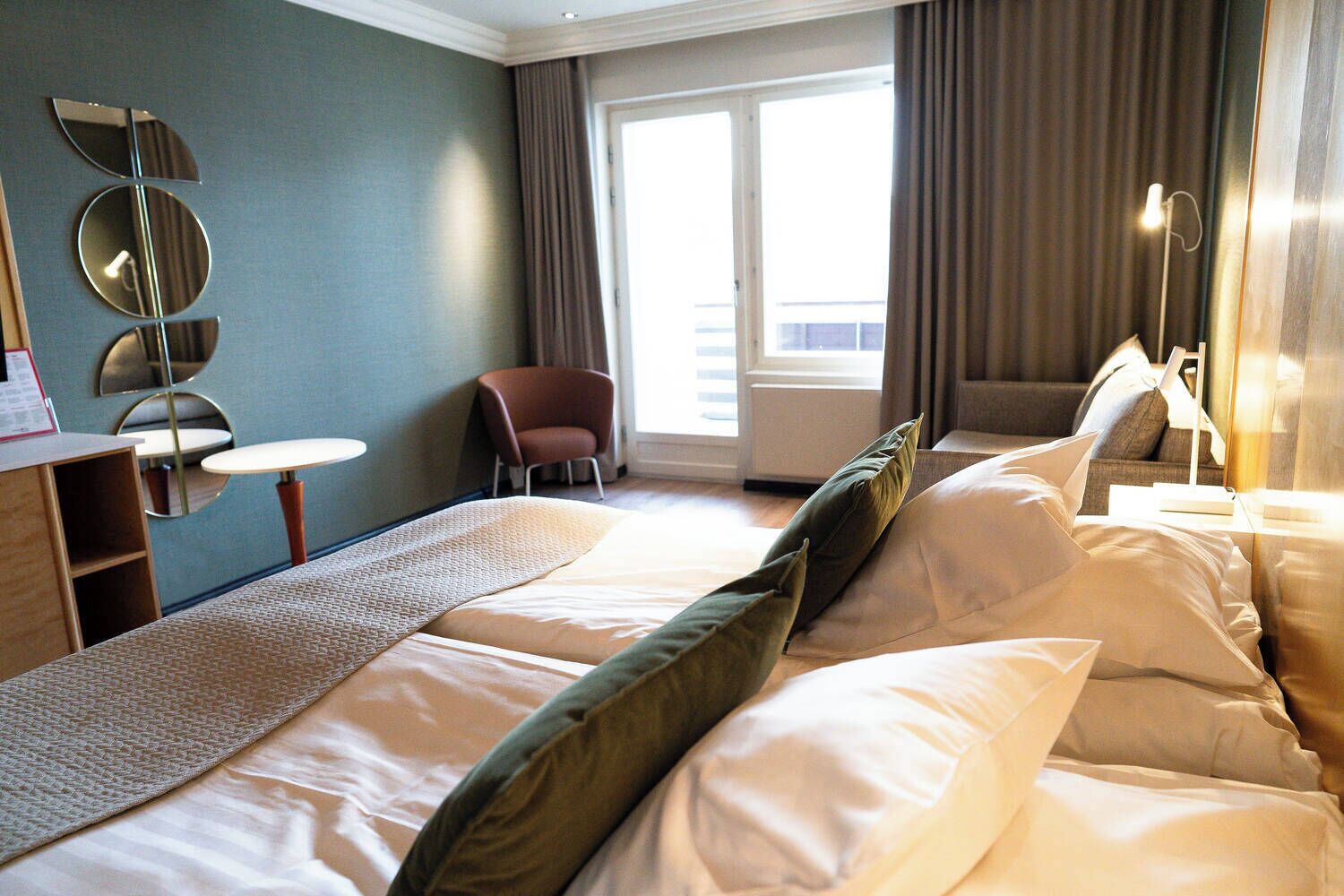 A hotel room with a large bed, a desk, a chair, and a sofa.